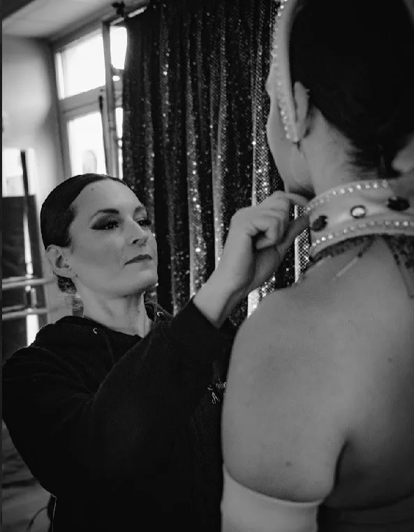 Costumière ajustant le costume d'une danseuse en coulisses